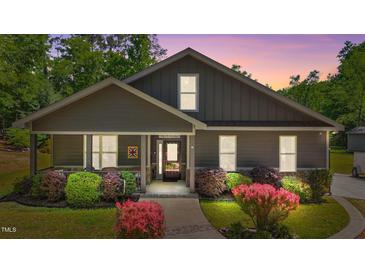 Charming home featuring a welcoming front porch and beautifully landscaped garden with colorful shrubs at 109 Rustler Rd, Louisburg, NC 27549