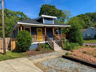 Charming home showcasing a vivid yellow door, complemented by a welcoming wooden porch and appealing blue siding at 1100 Chester St, Durham, NC 27701