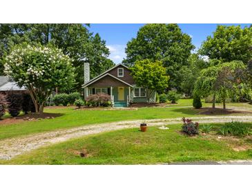 Charming home with lush front yard, mature trees, stone chimney, and a pop of color with a yellow front door at 209 E Winston St, Youngsville, NC 27596