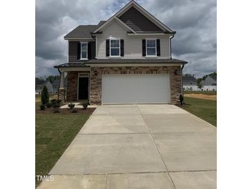 Two-story home with stone accents, a two-car garage, and a well-manicured front lawn at 364 Peach Grove Way, Lillington, NC 27546