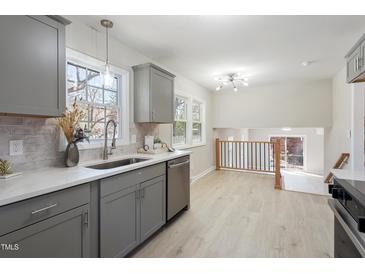 Well-lit kitchen with grey cabinets, stainless steel appliances, white countertops, and an open view to the dining area at 4204 Green Rd, Raleigh, NC 27604