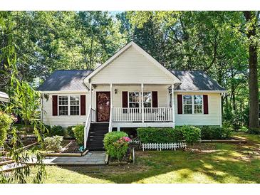 Charming one-story home with white siding, landscaped yard, and inviting front porch with railing at 5414 Stanley Rd, Durham, NC 27704