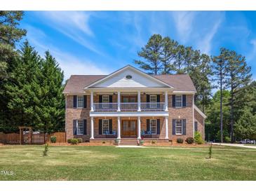 Stately brick home with a double porch and mature trees, offering classic curb appeal and southern charm at 55 Fleming Forest Dr, Youngsville, NC 27596