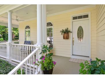 Charming front porch featuring white columns, ample seating, and a decorative front door at 7716 Micklewaithe Ct, Wake Forest, NC 27587