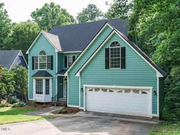 Charming two-story home with a blue-green exterior and attached two-car garage, framed by lush greenery at 816 Roanoke Dr, Cary, NC 27513