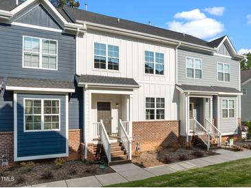 Charming townhome showcases a welcoming entrance with brick accents and blue and white siding under a bright blue sky at 820 Laurel Gate Dr, Wake Forest, NC 27587