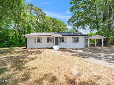 Charming white brick home featuring a metal roof, brown shutters, and a convenient carport at 8731 Raleigh, Benson, NC 27504