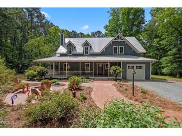 Charming two-story home features a long front porch, brick walkway, and beautifully landscaped front yard at 9625 Collins Creek Dr, Chapel Hill, NC 27516