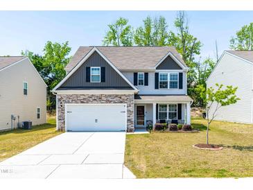 Charming two-story home with a manicured lawn, stone accents, and a welcoming front porch at 224 Brisk Dr, Zebulon, NC 27597