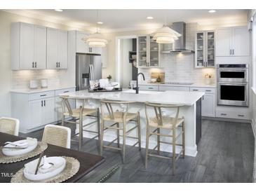 This kitchen features white cabinets, stainless steel appliances, an island with barstool seating, and modern lighting at 3725 Lebrun Path # 151 Lassen Fh, Fuquay Varina, NC 27526