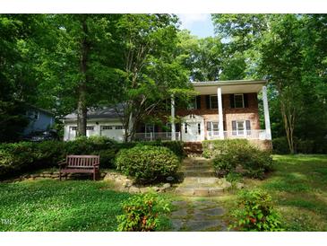 Charming brick home with a covered porch, lush landscaping, and a welcoming entrance at 4113 Oak Park Rd, Raleigh, NC 27612