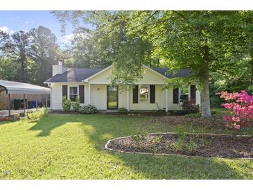 Charming single-story home with a well-manicured lawn and a cozy front porch nestled under lush greenery at 5300 Whippoorwill St, Durham, NC 27704