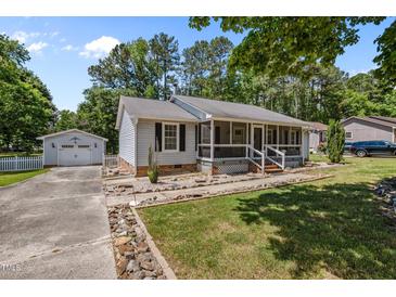 Charming single-story home featuring a screened-in front porch and a detached garage, enhanced by meticulous landscaping at 609 Chivalry Dr, Durham, NC 27703