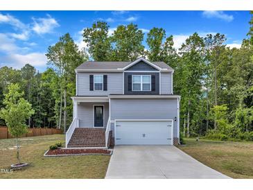 Charming two-story home with gray siding, brick stairs, a two-car garage, and a beautiful tree-lined background at 115 Parkers Gate Dr, Youngsville, NC 27596