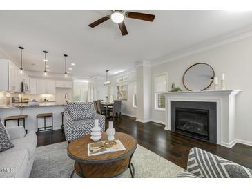 Open living room featuring a fireplace, ceiling fan, and dark hardwood flooring at 1211 Brown Velvet Ln, Apex, NC 27523