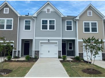 Charming townhome featuring a clean driveway, white garage, and complementary landscape for an inviting curb appeal at 247 Paramount Dr # 104, Smithfield, NC 27577