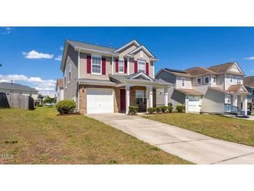Charming two-story home featuring a front-facing garage, red shutters, and well-maintained landscaping at 3629 Brittlebank Dr, Raleigh, NC 27610