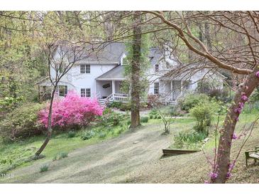 Charming white house with a covered front porch, surrounded by lush landscaping and flowering trees at 4 The Gln, Chapel Hill, NC 27514
