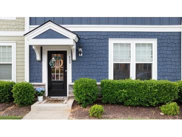 Charming front door with wreath, blue siding and neatly trimmed hedges at 433 Triumph Ln, Wake Forest, NC 27587