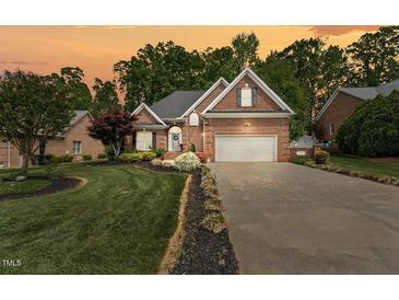 Beautiful brick home with a well-manicured lawn and two-car garage under a dramatic sunset sky at 480 Whitt Ave, Burlington, NC 27215