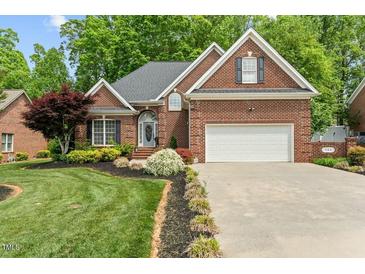 Charming brick home featuring a manicured lawn, attached two car garage, and lush landscaping at 480 Whitt Ave, Burlington, NC 27215