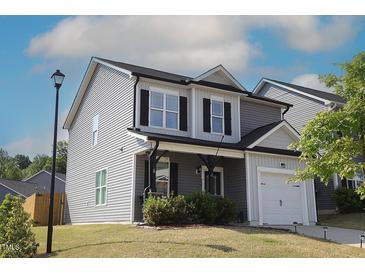 Charming two-story home featuring gray siding, black shutters and a well-manicured lawn at 49 Pumpkin Hill Rdg, Clayton, NC 27520