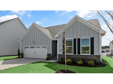 Charming home featuring vertical siding, black window shutters, a two-car garage, and well-maintained landscaping at 552 Lemon Daisy Ln, Knightdale, NC 27545