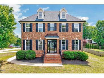 Charming brick two-story home with black shutters, dormers, well-manicured landscaping, and inviting entrance at 1009 Sarazen Dr, Clayton, NC 27527