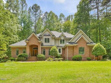 Stunning brick home featuring arched entry, manicured lawn, and mature trees at 1428 Gray Bluff Trl, Chapel Hill, NC 27517