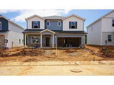 Two-story home with blue and white siding and an open garage, presenting an unfinished landscape at 2226 Cherry Creek Rd, Haw River, NC 27258