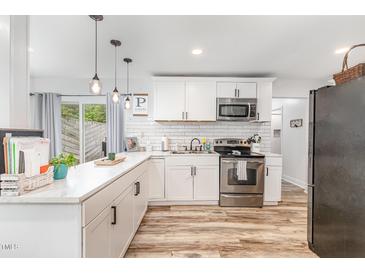 Bright kitchen with stainless steel appliances, subway tile backsplash and white cabinetry at 2746 Saint Lukes Church Rd, Goldston, NC 27252