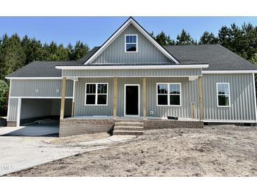Charming single-story home boasts a welcoming porch, gray siding and an attached garage with natural light and a yard to be landscaped at 2802 Packing Plant Rd, Smithfield, NC 27577
