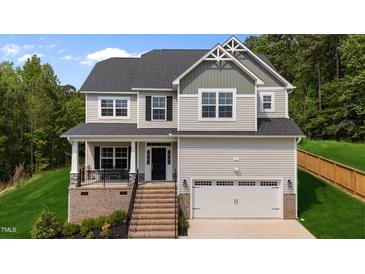 Charming two-story home featuring a covered porch, attached garage, and meticulously landscaped front yard at 5 Cinnamon Teal Way, Youngsville, NC 27596
