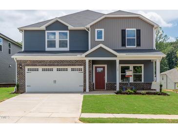 Charming two-story home featuring a brick and vinyl exterior, a two-car garage, and a well-manicured lawn at 729 Deschutes Dr, Garner, NC 27529