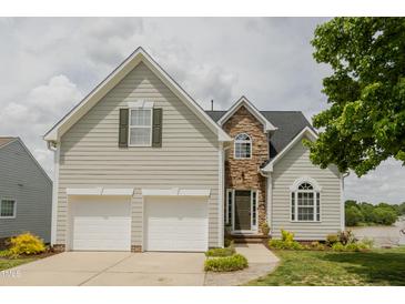 Charming home with a two-car garage, stone accents, a manicured lawn, and beautiful landscaping at 1003 Southshore Pkwy, Durham, NC 27703