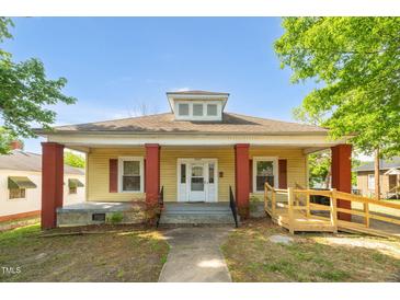 Charming single-story home featuring a welcoming front porch, vibrant red columns, and a convenient wheelchair ramp at 1007 Grace Ave, Burlington, NC 27217