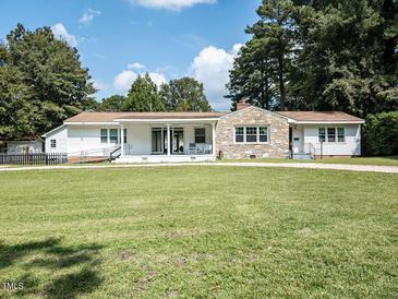 Charming single-story home featuring a stone accent wall, a covered porch and a spacious front yard at 110 W Parker St, Smithfield, NC 27577