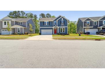 Two-story home boasts a blue exterior, red door, and a well-maintained front yard at 244 Potomac River St, Garner, NC 27529