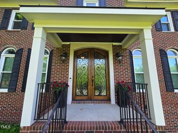 Elegant brick home featuring a decorative wrought iron double-door entrance and covered porch at 5025 Martin Farm Rd, Raleigh, NC 27613