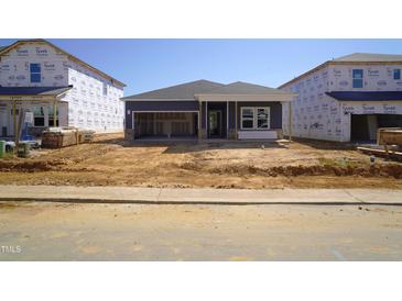 New home construction with a blue facade, featuring an open garage and a partially landscaped yard at 648 White Birch Ln, Angier, NC 27501