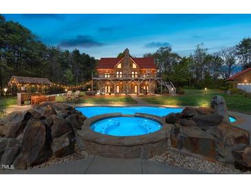 Beautiful log home featuring a swimming pool, jacuzzi, and an outdoor tiki bar surrounded by lush greenery at 6707 Frieden Church Rd, Gibsonville, NC 27249