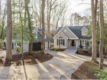 Charming grey house with a two-car garage, surrounded by mature trees and a long driveway at 7116 Asheway Dr, Holly Springs, NC 27540