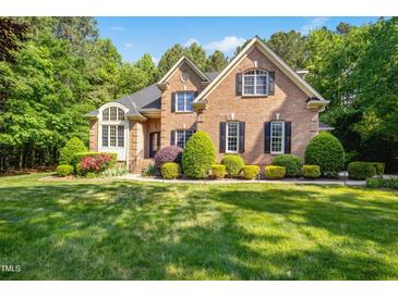 Beautiful brick home with manicured lawn, flowering shrubs, and mature trees for an inviting curb appeal at 10011 Hammock Bnd, Chapel Hill, NC 27517