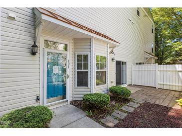 Inviting townhome entrance featuring a bright blue door, manicured landscaping, and a charming covered porch at 11710 Mezzanine Dr # 101, Raleigh, NC 27614