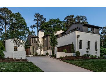 Stunning two-story home featuring a painted brick exterior, dark trim, manicured lawn and driveway at 1222 Duplin Rd, Raleigh, NC 27607