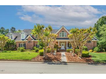 Beautiful brick home featuring a manicured lawn, professional landscaping, and inviting front entrance at 129 Trellingwood Dr, Morrisville, NC 27560