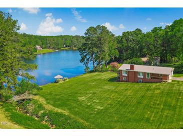 Beautiful waterfront property featuring a well-maintained lawn and a charming house overlooking the serene lake at 1415 Clearwater Dr, Sanford, NC 27330