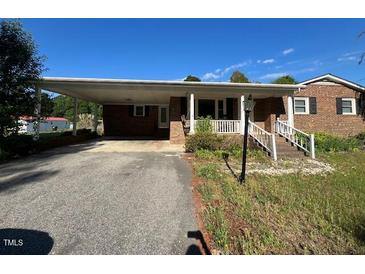 Quaint brick home featuring a covered carport and a charming front entrance with a white railing at 167 Chic Ennis Rd, Coats, NC 27521