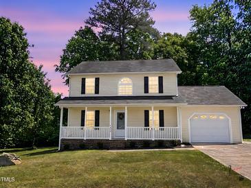 Charming two-story home with a welcoming front porch and well-maintained lawn at dusk at 3609 Cold Harbour Dr, Raleigh, NC 27610