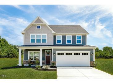 Two-story home with a two-car garage, covered porch and manicured lawn under a bright blue sky at 569 Freedom Trail Dr, Willow Springs, NC 27592